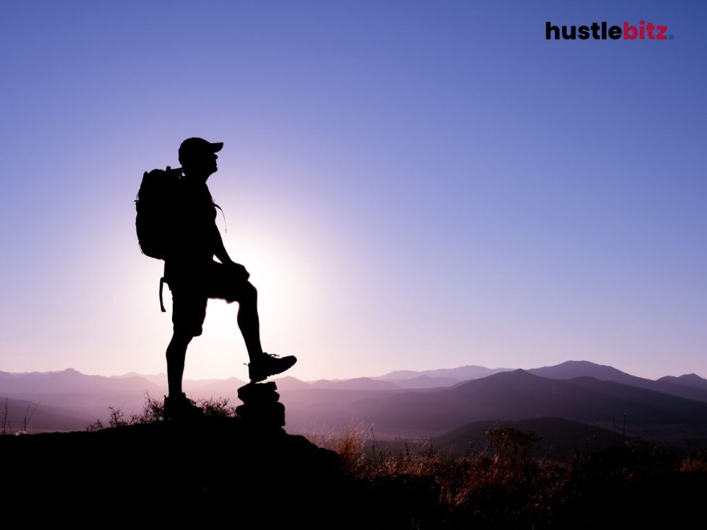 A hiker man step the stone while looking at the mountains