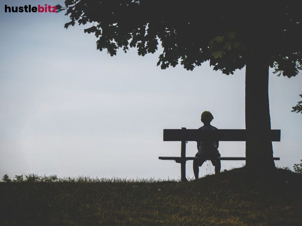 A person sitting on the bench beside the tree