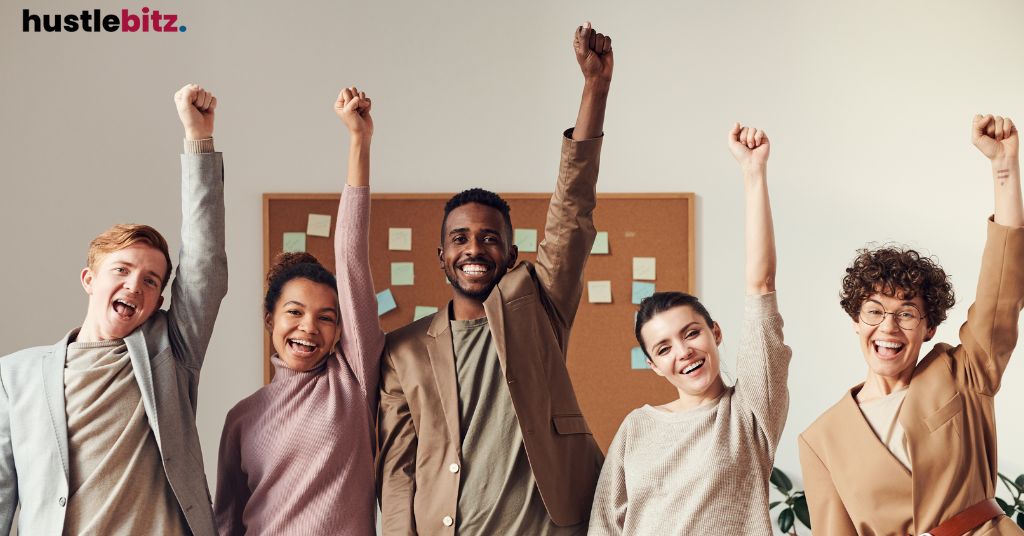 A group of employee smiles and raise their hands