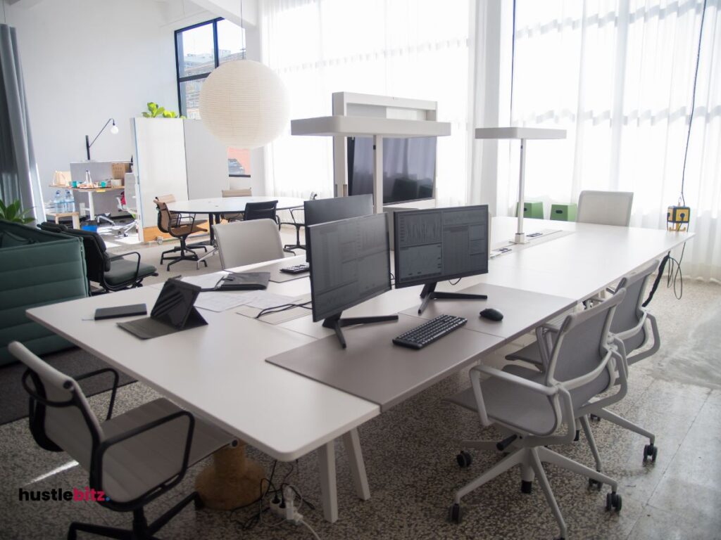 A room with two monitor, table and chairs