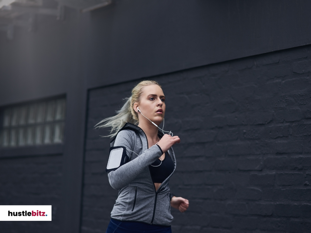 A woman wearing a headset jogging  on the street.