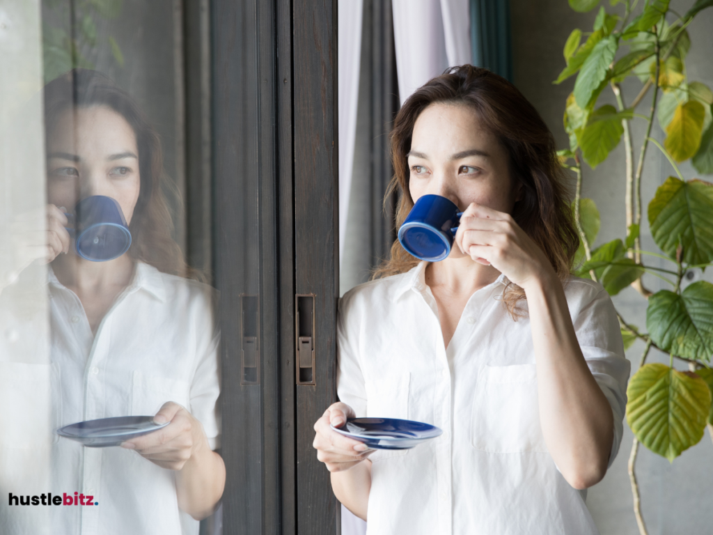 A woman drinking her morning tea beside the window.