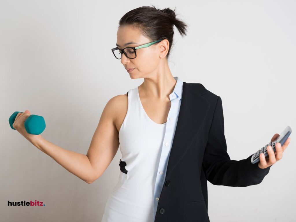 A woman holding a dumbbell in one hand and a calculator on another.