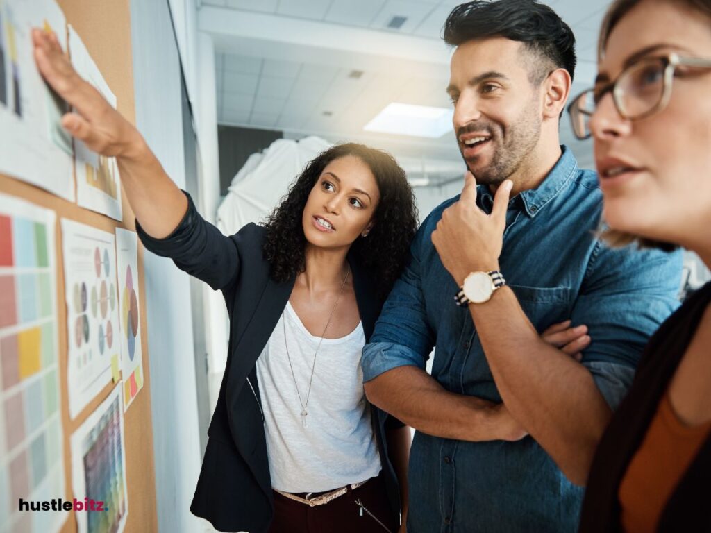 Three persons looking at the bulletin board discussing.