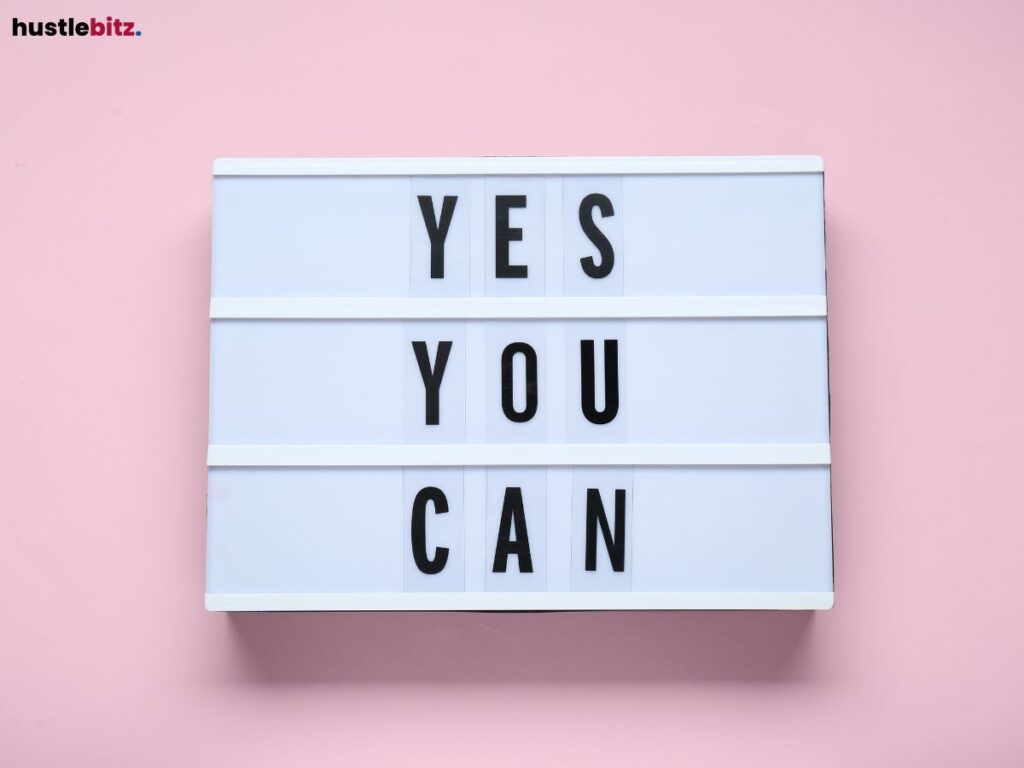 A white board with "YES YOU CAN" written on it, against a pink background.