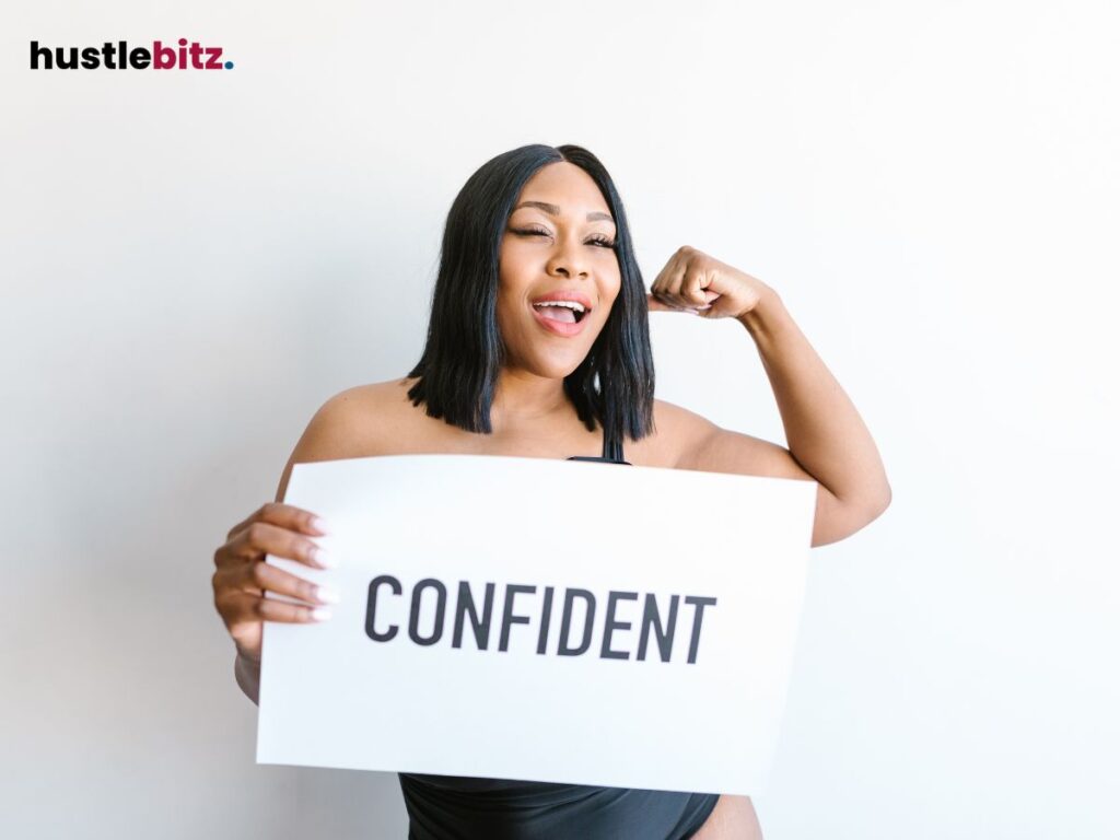 A woman smiles confidently, holding a sign that reads "CONFIDENT."