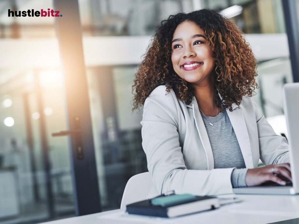 A woman smiles confidently while working at a bright, modern office.