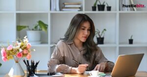 A woman inside the office with laptop and bookshell background