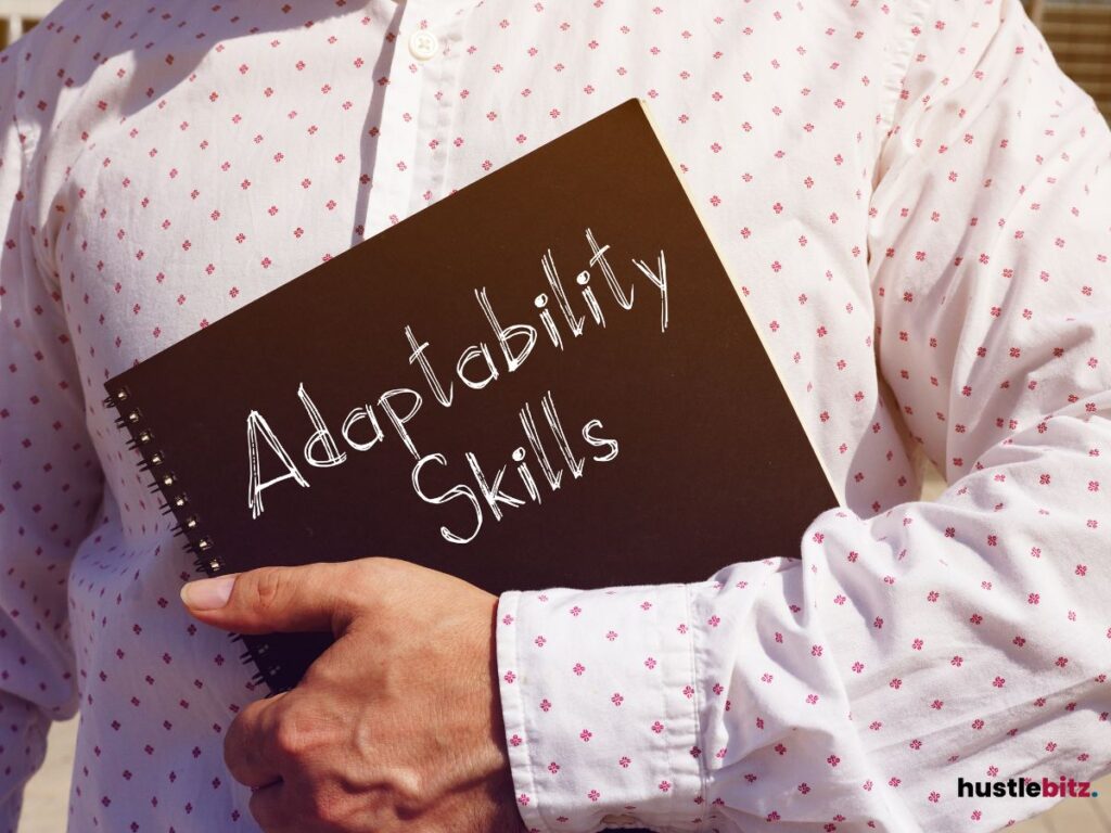 A man holding a black notebook with words: ADAPTABILITY SKILLS