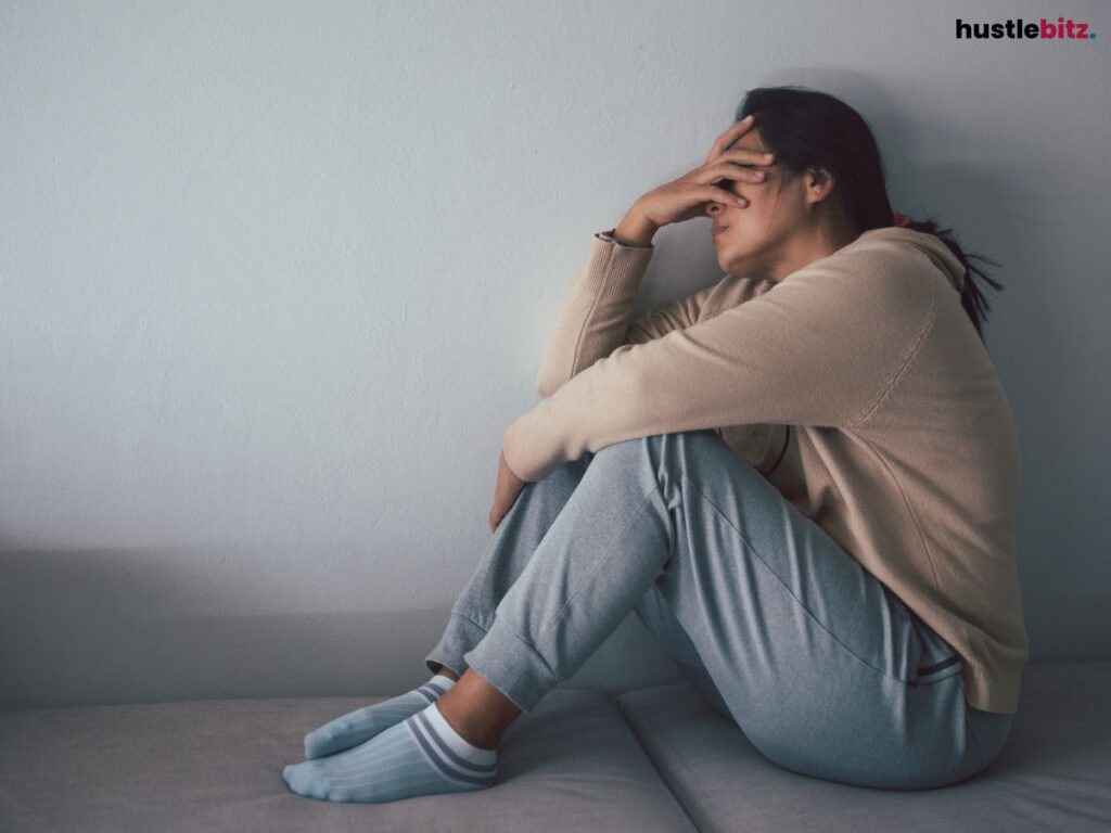 A woman sitting while holding her head