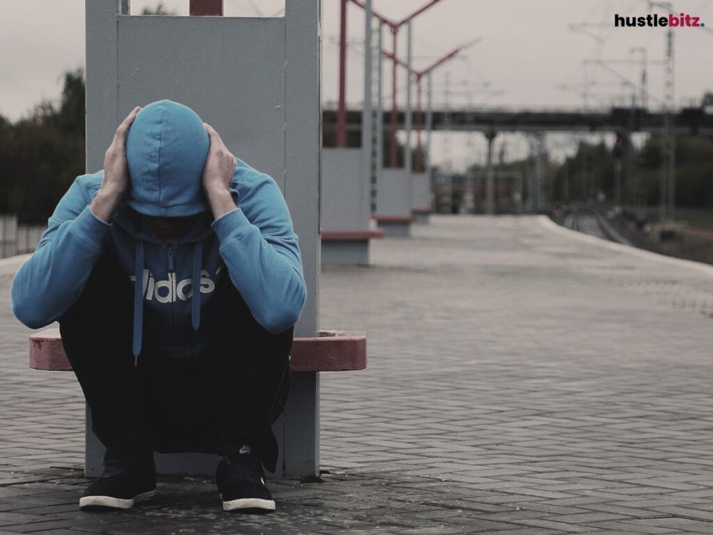 A man crouching down, holding his ears.