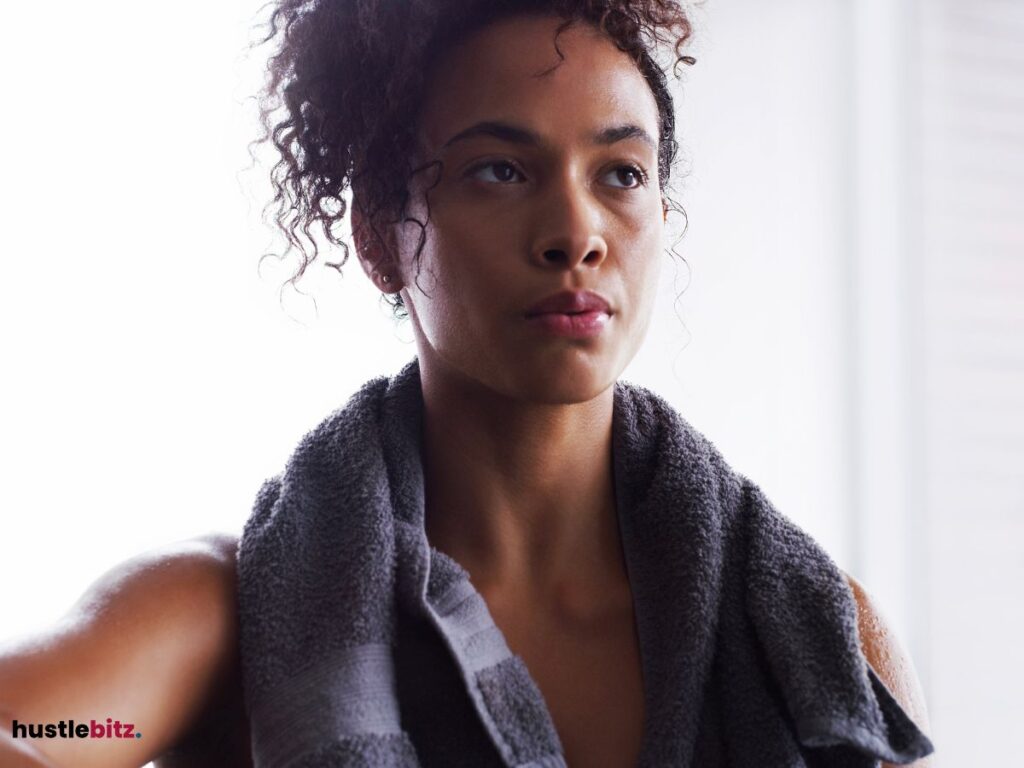 Woman with a towel over her shoulder, staring ahead.