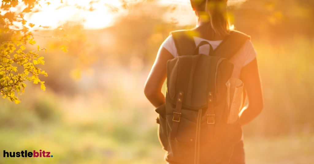 Person with a backpack walking into a sunlit forest.