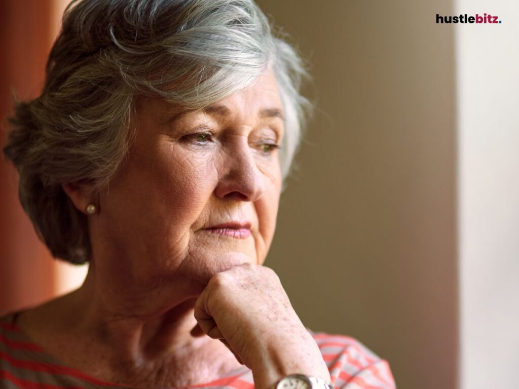  Elderly woman looking thoughtfully out a window.
