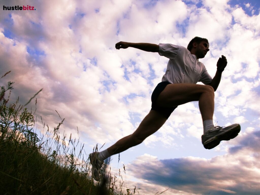  Person running uphill, with the sky and grass in the background.
