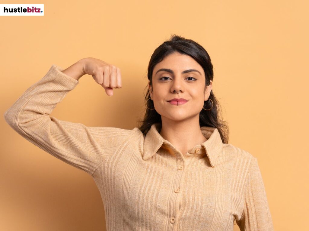 A woman flexing her muscles in orange background.