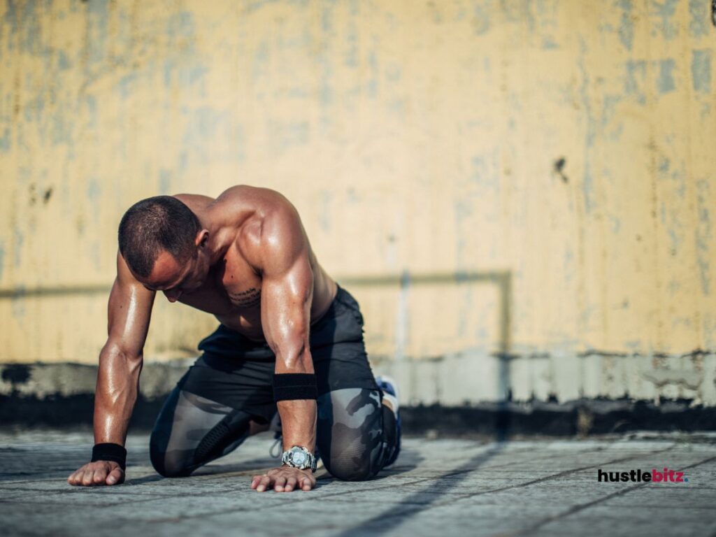 A man crouching down, tired from workout.