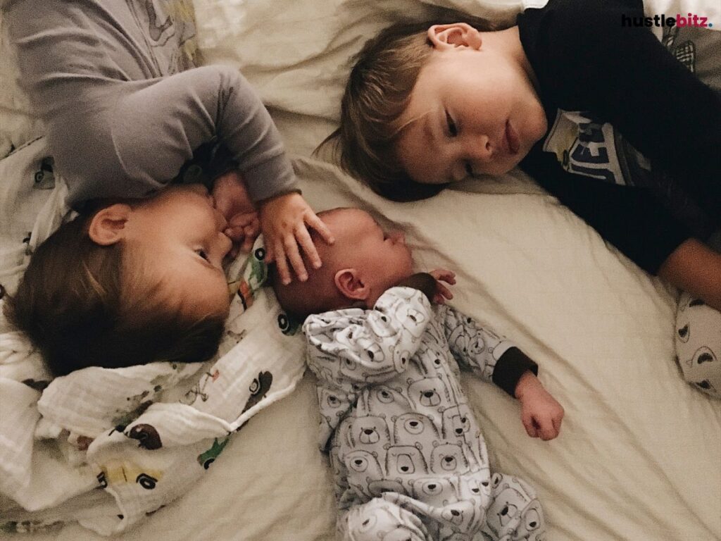 Siblings lying down in the bed.