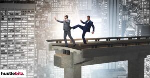 A man kicking a blindfolded man in the end of the bridge.