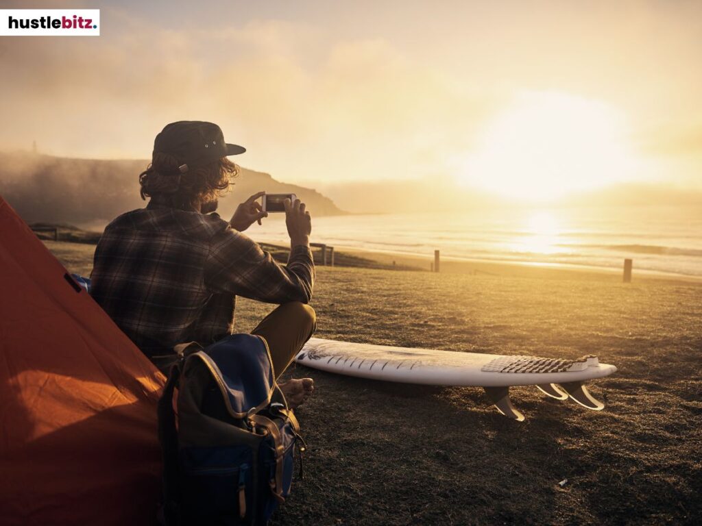 A man taking a picture of the sunset.