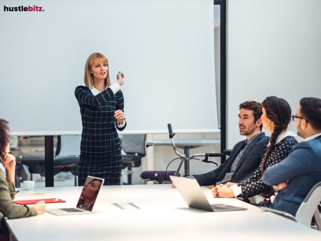 A woman presenting to a group in a modern office setting, smiling confidently.