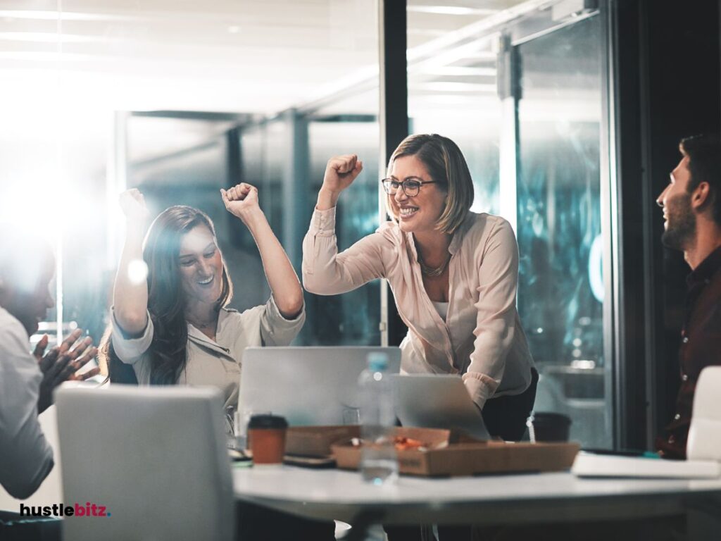 A group of coworkers celebrating a success around a table in an office.