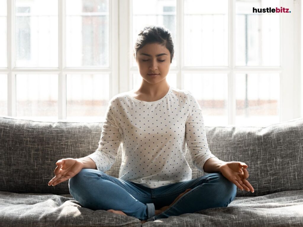 A woman meditating on a couch.