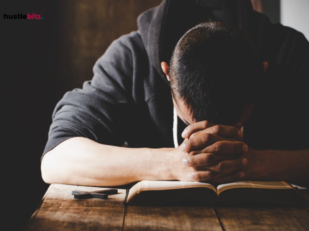 A man with his head bowed over a book, deep in thought or prayer.