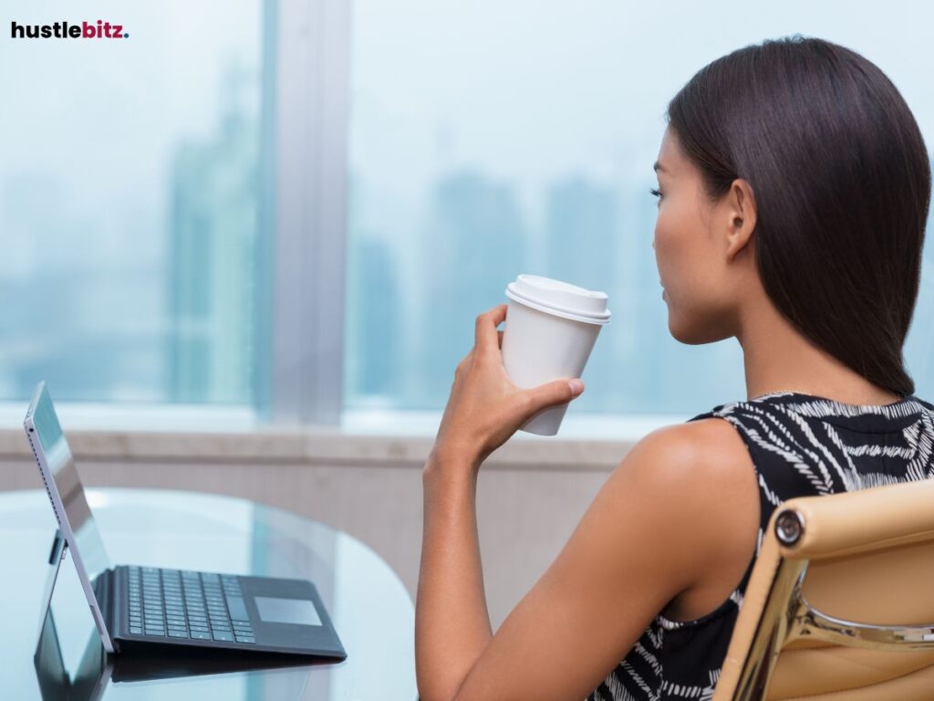 A woman sitting on the office holding a cup of coffee.