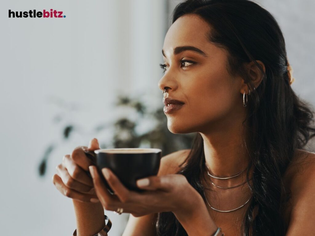 Woman holding a cup of coffee, looking thoughtfully into the distance.