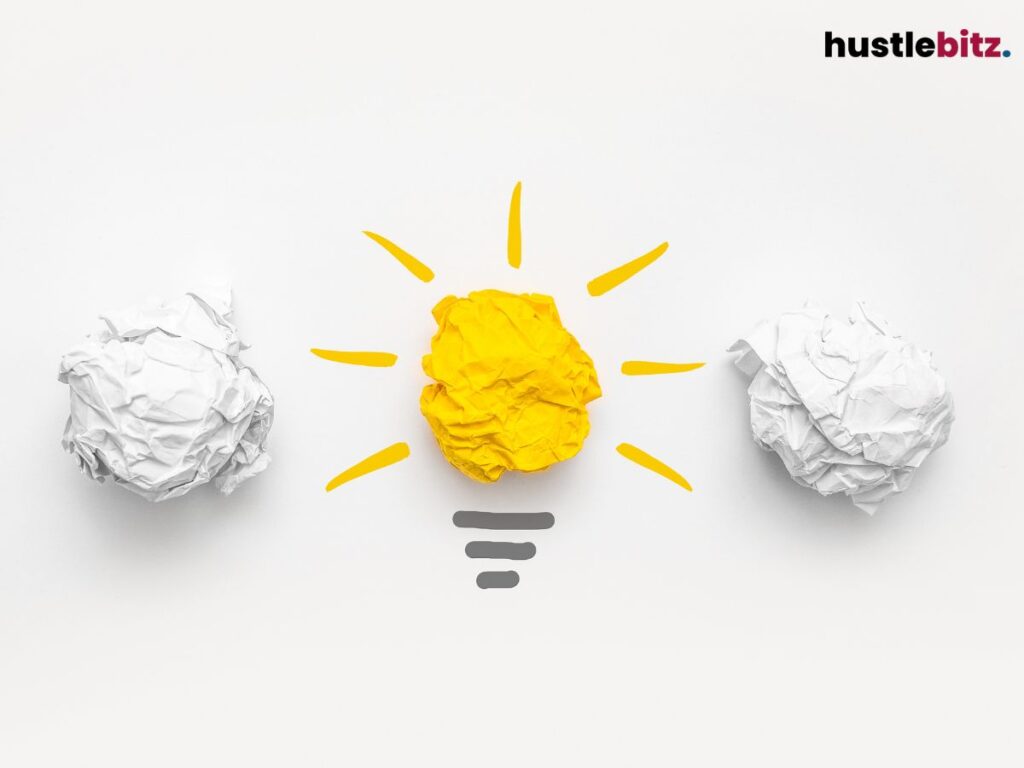 A crampled yellow paper looks like a lightbulb with two white crampled paper beside it.