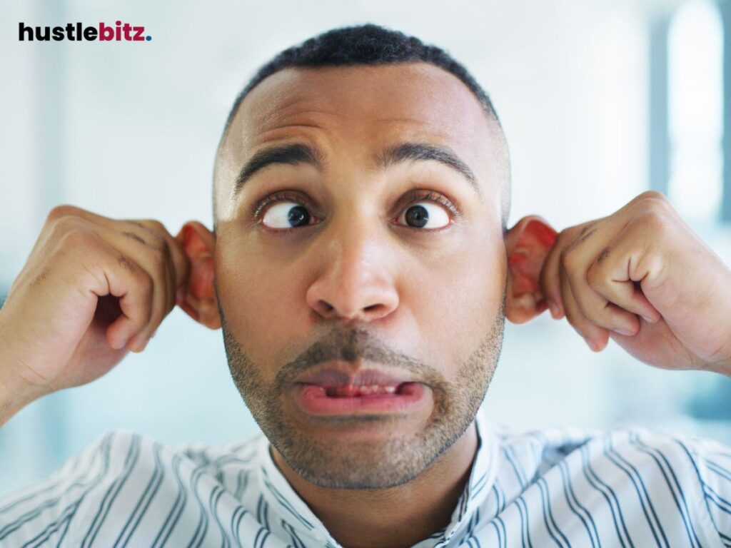 A man making a silly face by pulling his ears and crossing his eyes.